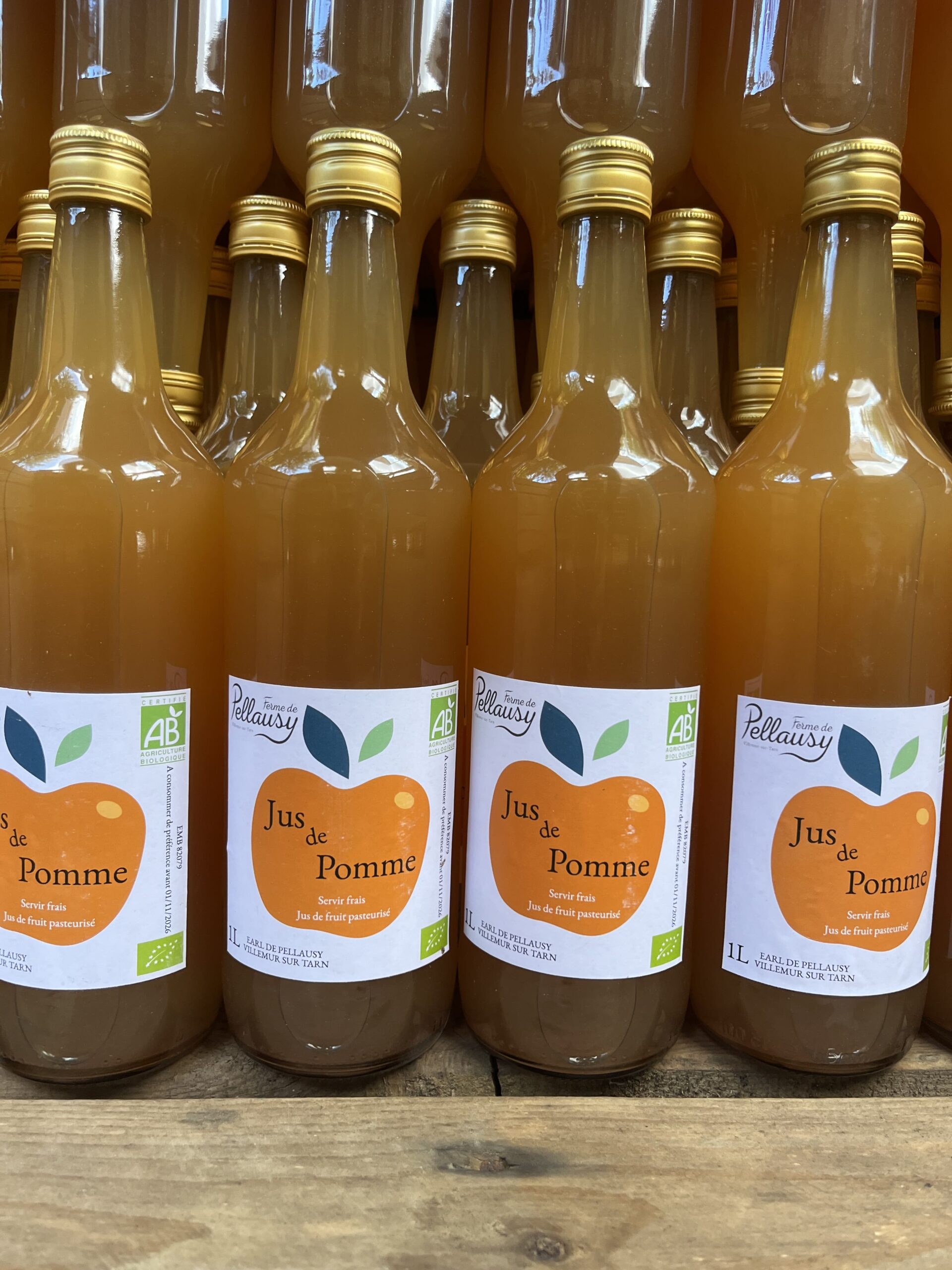 Bouteilles de jus de pomme bio Ferme Pellausy alignées en rayon à villemur-sur-tarn